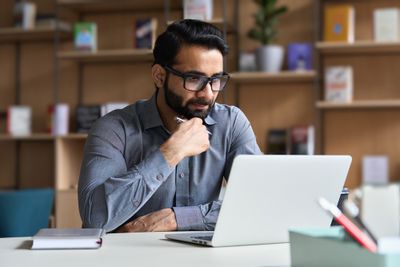 Shopify seller sitting at a desk looking at a laptop