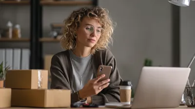 a woman sitting in front of a laptop, there's boxes next to her