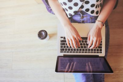 Shopify store owner using a laptop computer on top of a wooden floor to create custom filters