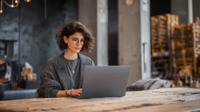 a woman sitting at a table using a laptop computer
