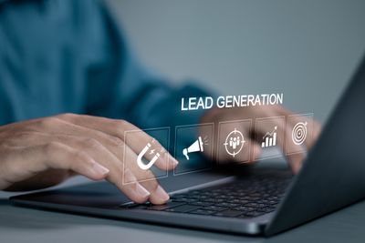 An eCommerce seller typing on a laptop with the word lead generation hovering above it