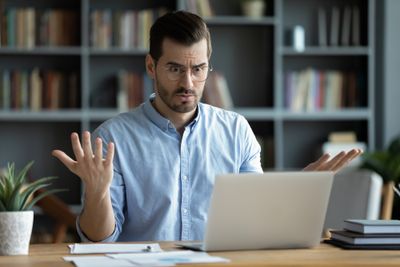 Shopify seller sitting in front of a laptop looking confused while trying to cancel his Shopify domain