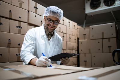 Factory worker sorting products with a lab coat and clipboard