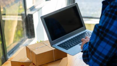 Man holding laptop and examining packed and wrapped boxes