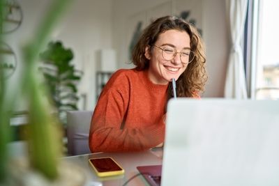 An excited Shopify store owner sitting in front of a laptop computer testing image optimization