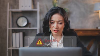 A woman sitting in front of a laptop computer looking at the error 404 code on her screen