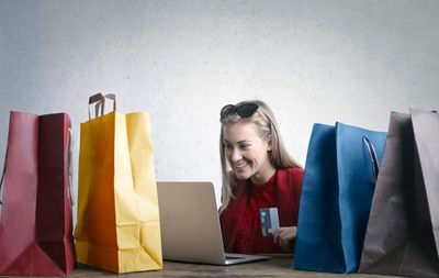 a woman sitting in front of a laptop computer surrounded by shopping bags