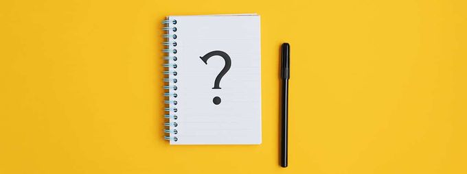 a notepad with a question mark on it next to a pen