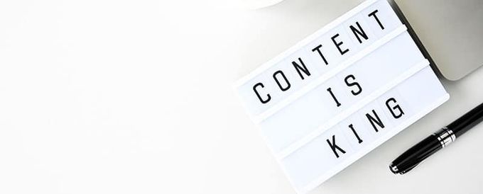 a note that says content is king next to a laptop