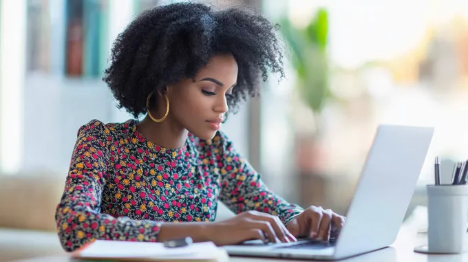 a woman sitting at a table using a laptop 