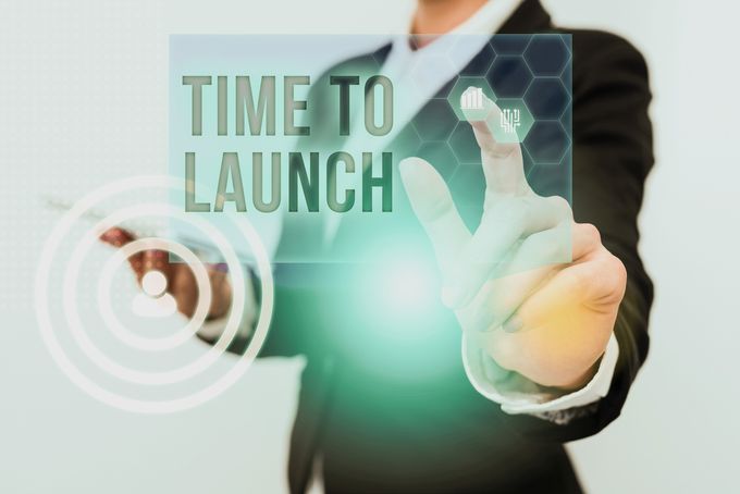 Shopify store owner in a suit holding a sign that says time to launch