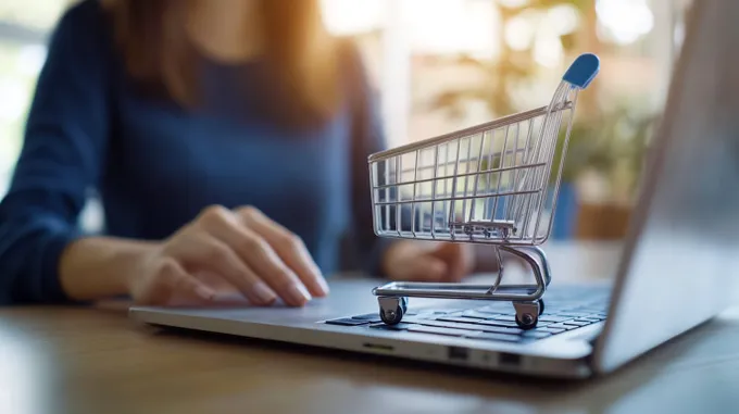 a woman using a laptop computer with a shopping cart on top of it