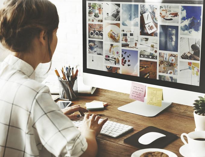 A woman sitting at a desk working on her product image sizes for Shopify.
