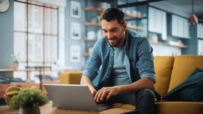 Shopify seller sitting on a couch using a laptop to manage his Shopify store