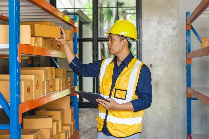 Worker checking stock on shelf in warehouse