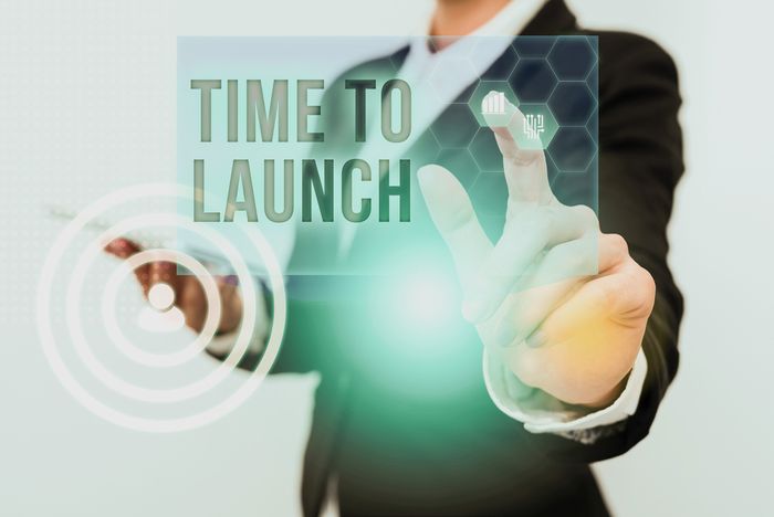 Shopify store owner in a suit holding a sign that says time to launch