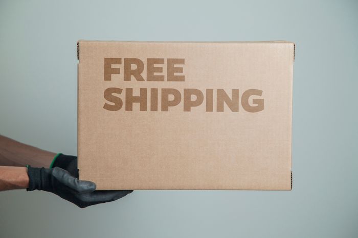 Shopify seller holding a cardboard box with the words free shipping written on it
