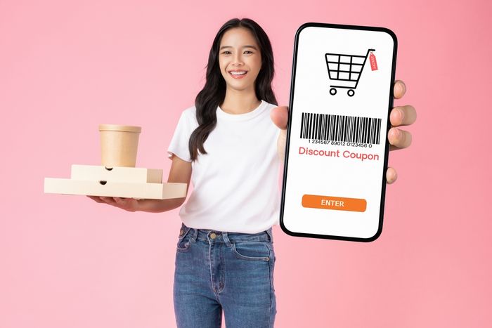 Woman holding up a cell phone with a bar code on it for a discount coupon