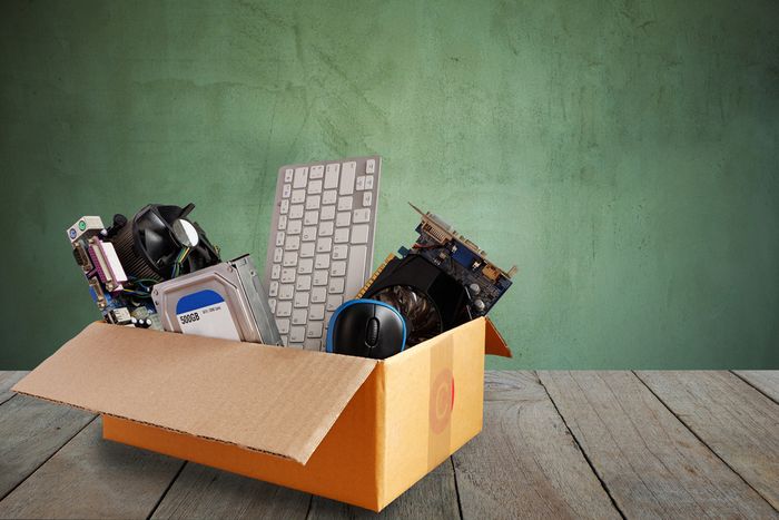 Cardboard box filled with old obsolete inventory items on top of a wooden table
