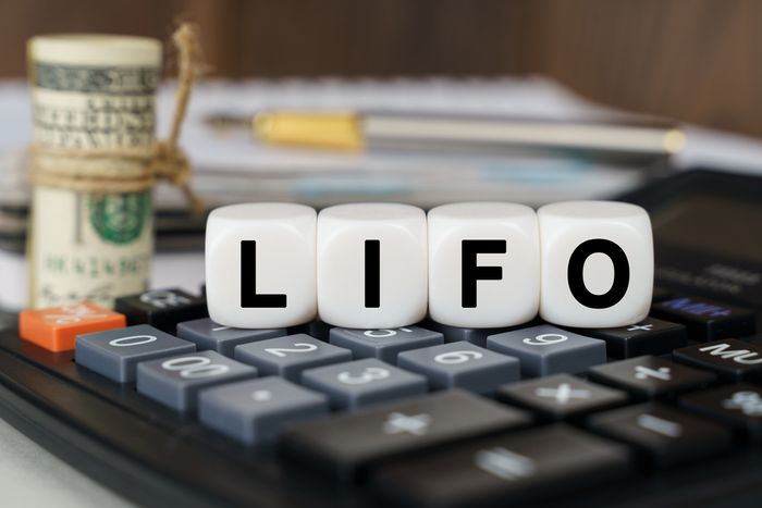 A calculator sitting on top of a desk beneath dice that read "LIFO"