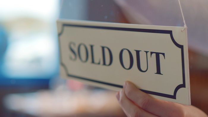 A hand holding a sign that says sold out