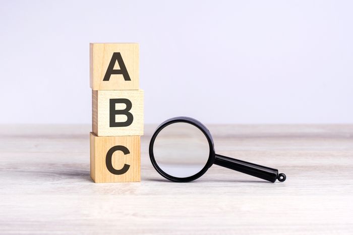 Magnifying glass sitting next to wooden blocks spelling ABC