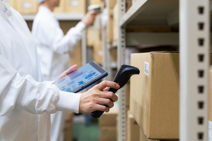 eCommerce worker in a warehouse holding a tablet and scanner against product ID