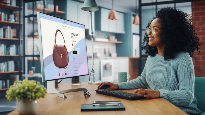 Shopify store owner sitting at a desk in front of a computer managing handbag collections