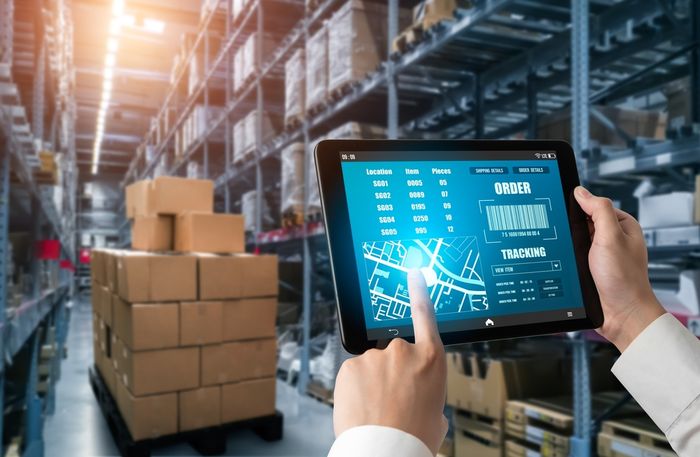Shopify seller holding a tablet in a warehouse measuring inventory to sales ratio