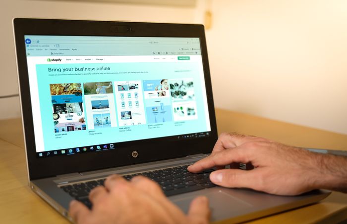 A man is working on his Shopify store on a laptop computer