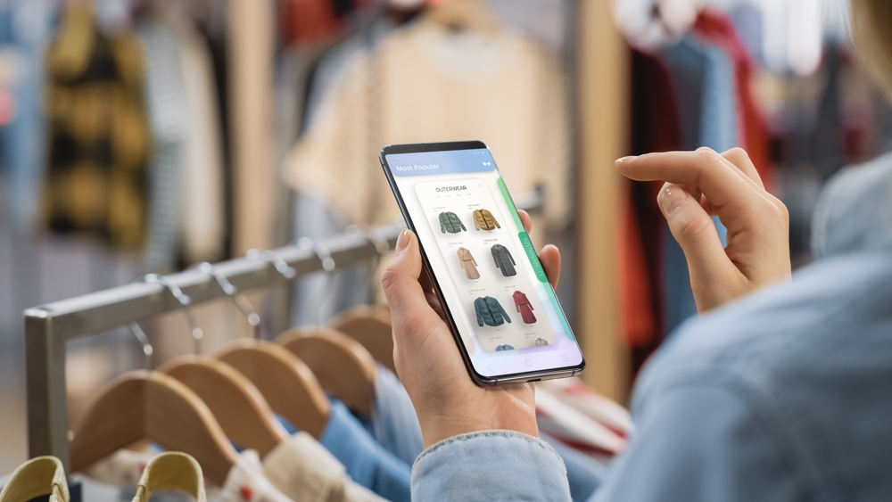 a woman looking at a cell phone and sorting the display of shoes based on product type