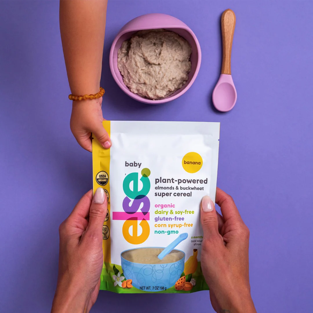 a person holding a bag of baby food next to a bowl of food