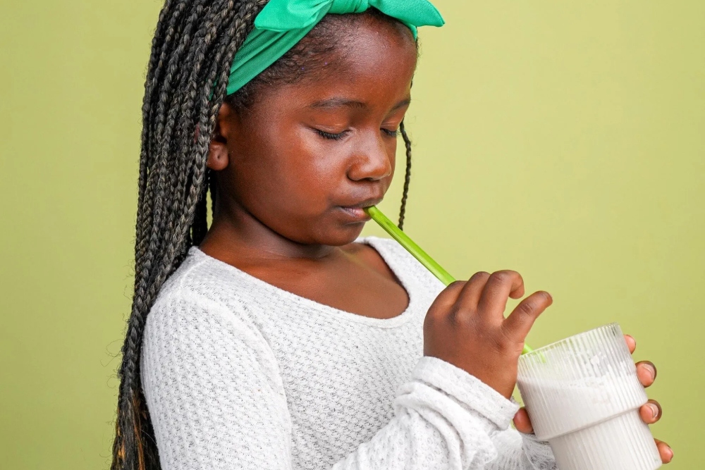 a little girl drinking from a cup while holding a straw