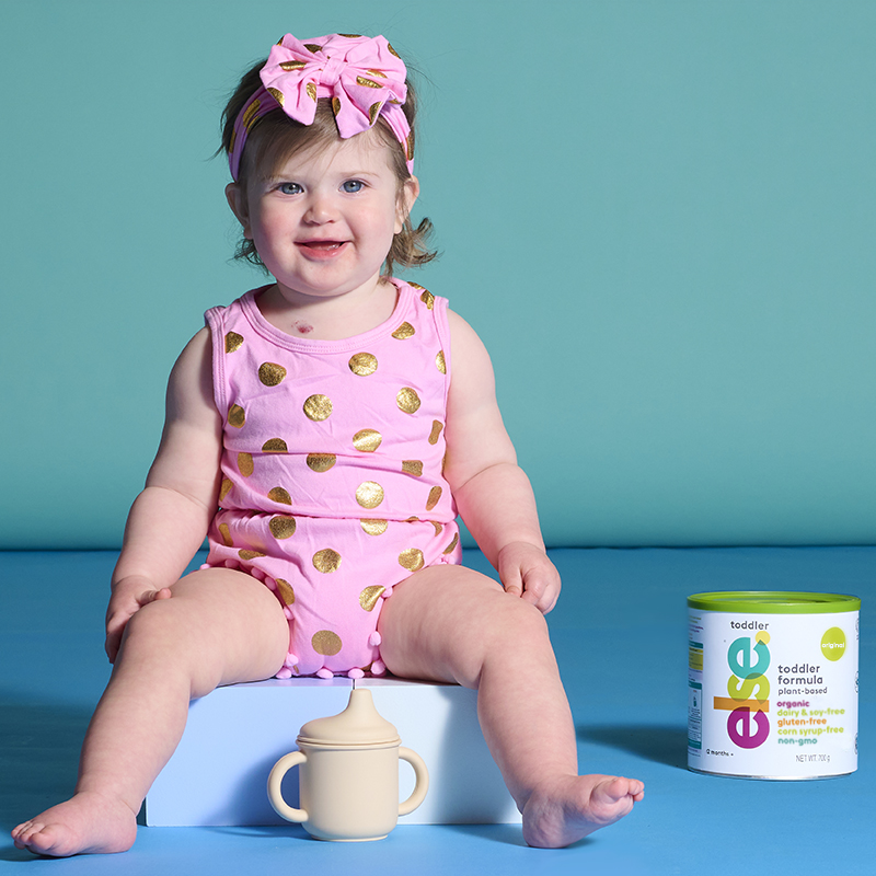 a little girl sitting on a  can of dairy free and soy free formula