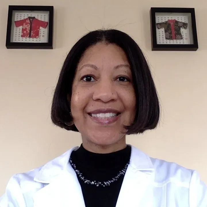 a woman in a lab coat standing in front of two framed pictures