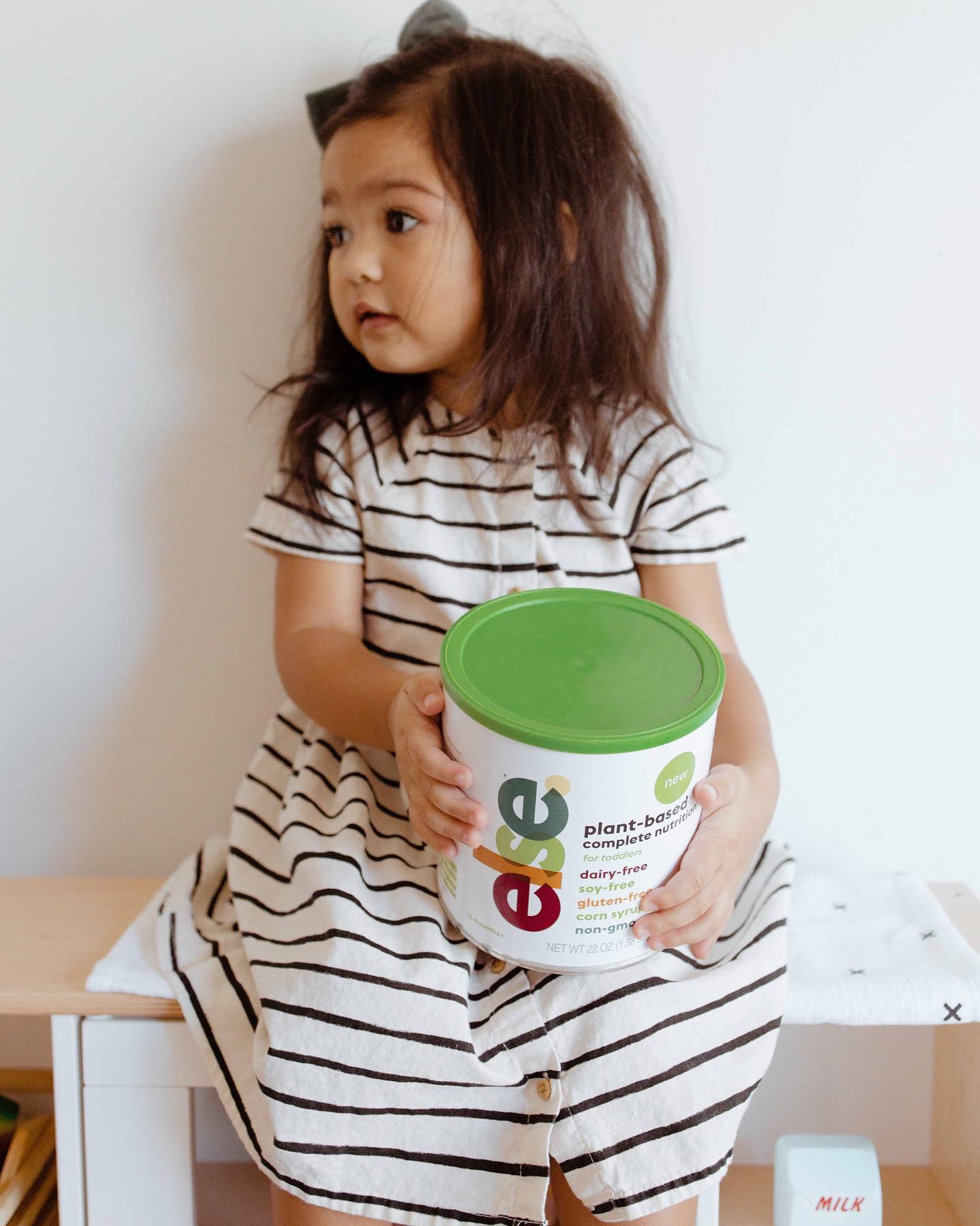a little girl sitting on a table with else nutrition toddler formula