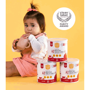 a little girl sitting on the floor with four cans of baby formulas