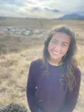 a woman standing in a field with mountains in the background