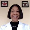 a woman in a lab coat standing in front of two framed pictures