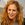 a woman with curly red hair smiling at the camera