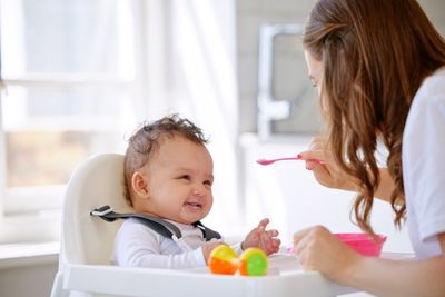 A woman feeding a baby with a spoon.