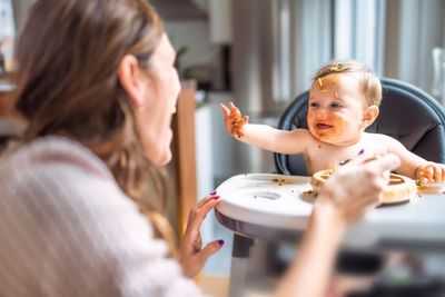 A mother feeding her baby healthy food.