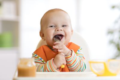 A baby sitting in a high chair eating food.