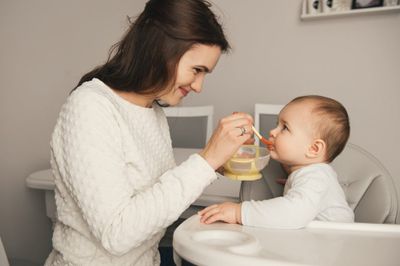 A woman feeding a baby with a spoon.