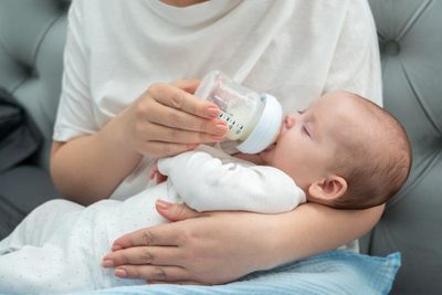 A woman feeding a baby with a bottle.