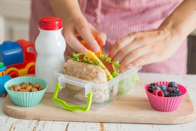 a person putting a sandwich in a plastic container