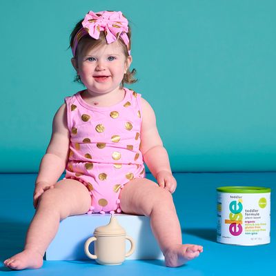 a little girl sitting on a  can of dairy free and soy free formula