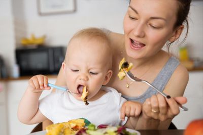 a woman feeding a baby a piece of food