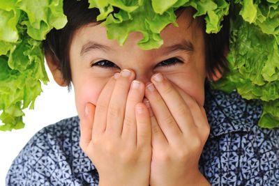 a young boy covering his face with his hands