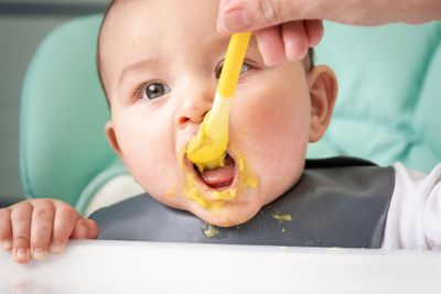 a baby in a high chair eating food with a spoon